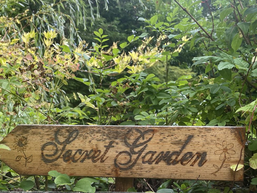 A wooden sign labeled Secret Garden surrounded by plants in a garden at DeCressy Apartment Par