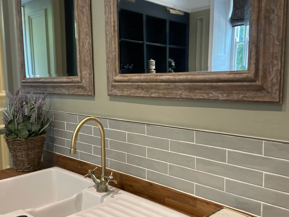 A kitchen sink with a tap and mirrors at Garden Apartment in Par