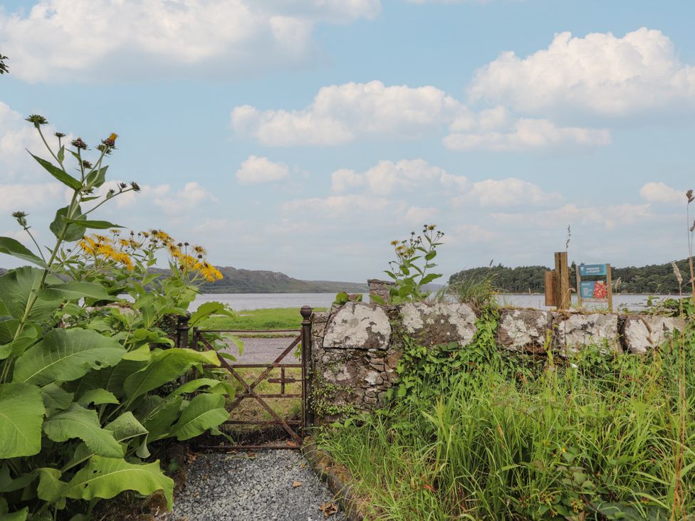 A view through a gate and stone wall towards a lake at Sron Dubh Achnasheen