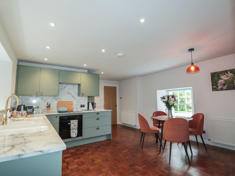 A kitchen with cabinets and dining table at Sron Dubh in Achnasheen