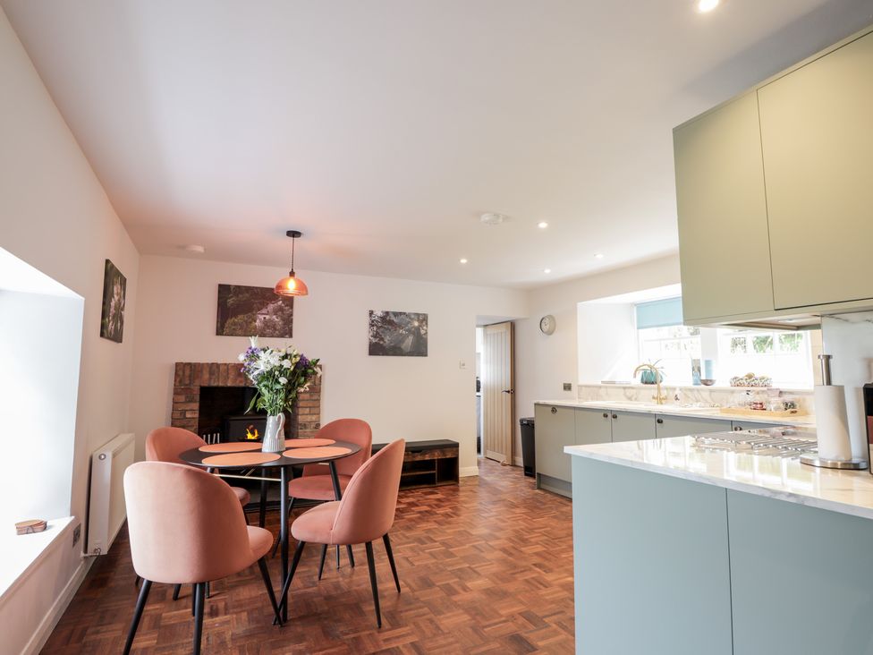A kitchen with table and chairs next to a fireplace at Sron Dubh in Achnasheen