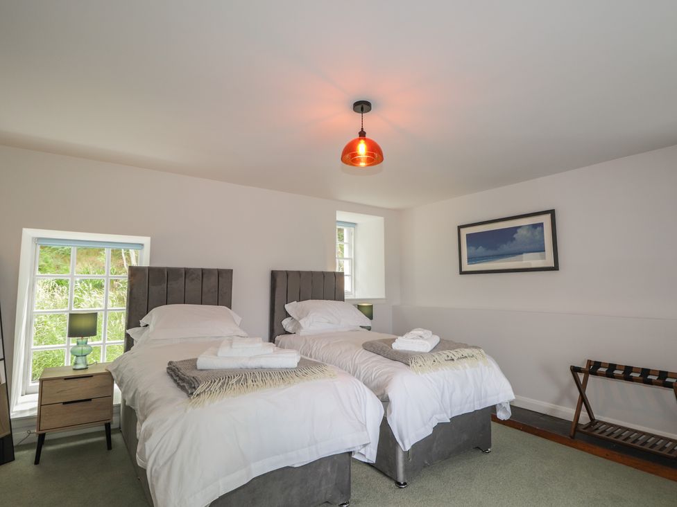 A bedroom with two beds, nightstand, lamp and window at Sron Dubh Achnasheen
