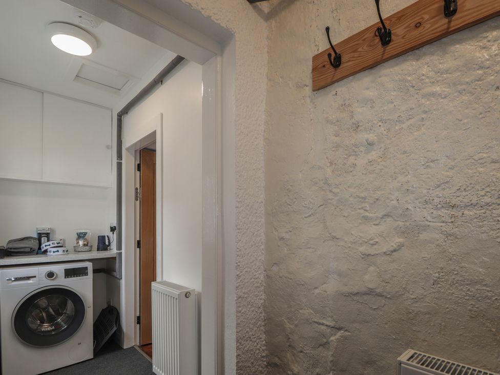 A laundry room with a washing machine and shelves at Sron Dubh in Achnasheen