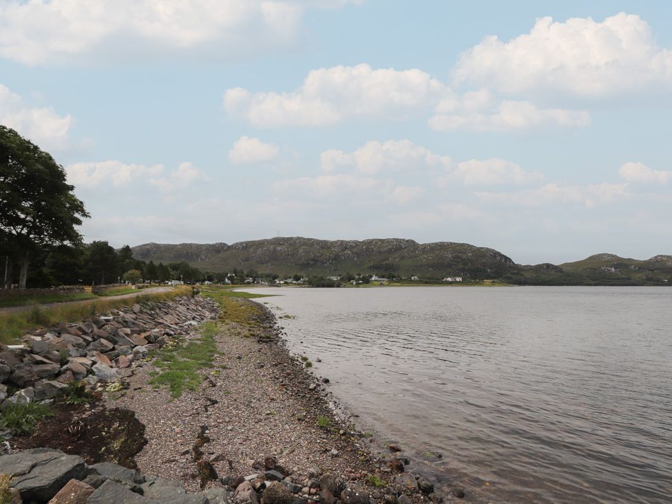 A shoreline with water, stones, and trees at Sron Dubh in Achnasheen