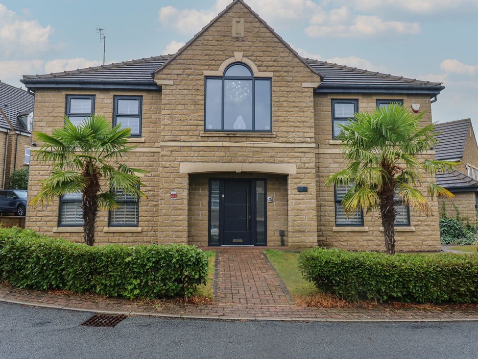 A house with palm trees and a front door at 20 Overland Crescent in Apperley Bridge