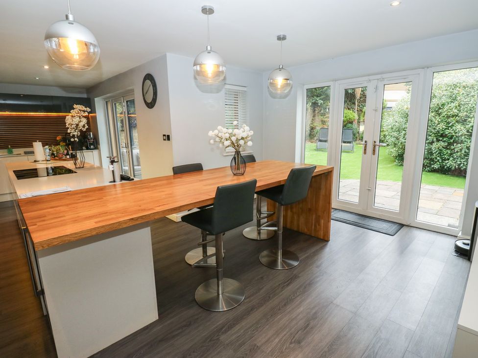 A kitchen with a large island and bar stools at 20 Overland Crescent, Apperley Bridge