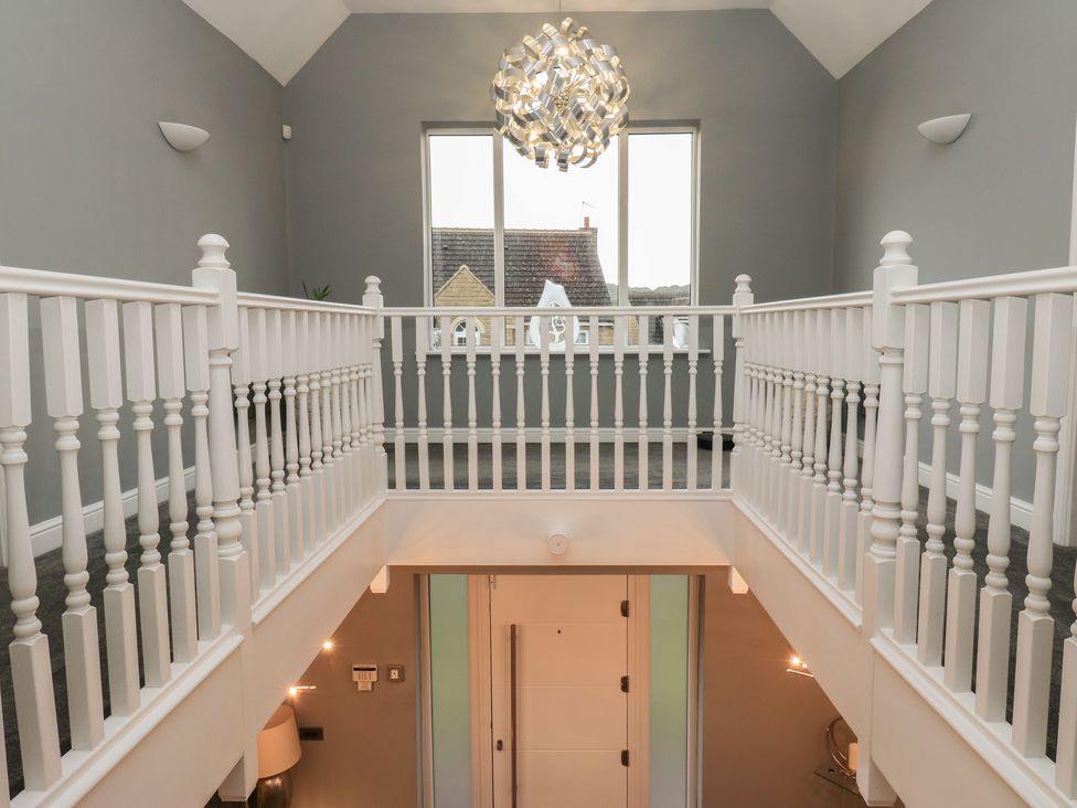 A hallway with a staircase and light fixture at 20 Overland Crescent in Apperley Bridge
