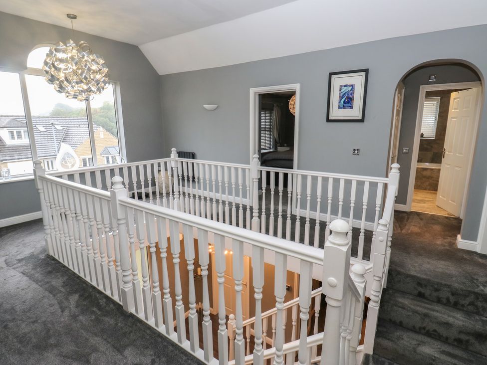 A hallway with a staircase and ceiling light at 20 Overland Crescent in Apperley Bridge
