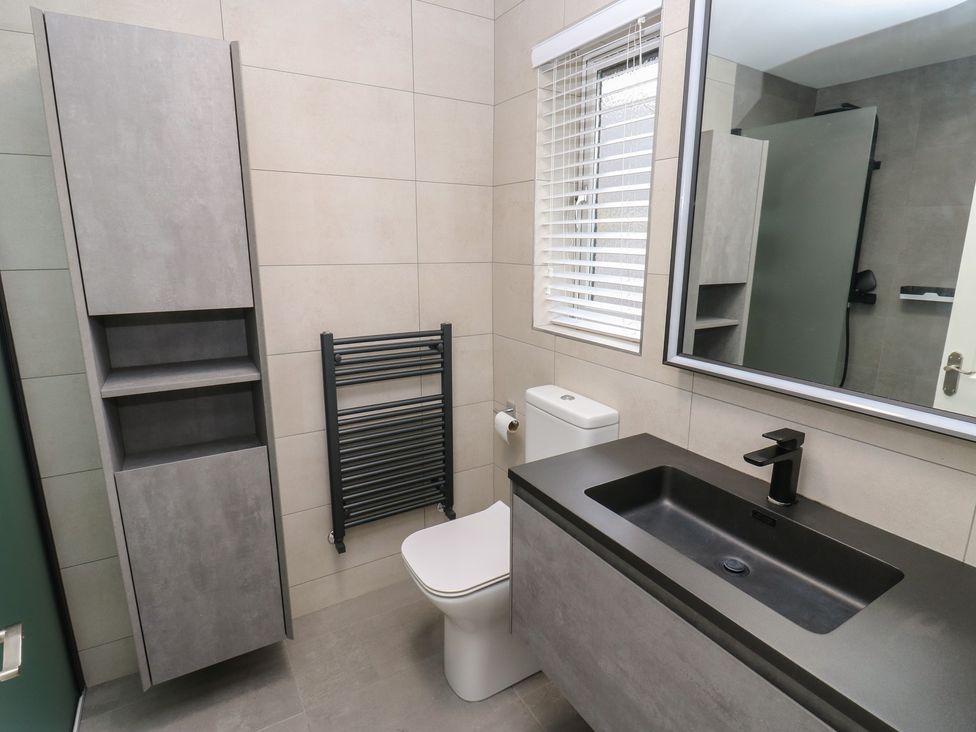 A bathroom with a sink, toilet, and cabinet at 20 Overland Crescent in Apperley Bridge