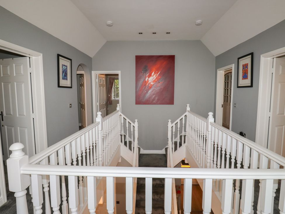 A hallway with a staircase and artwork on the walls at 20 Overland Crescent in Apperley Bridge