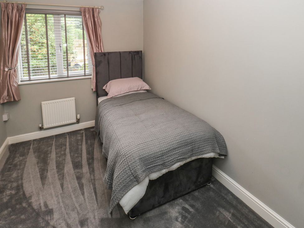 A bedroom with a single bed and window at 20 Overland Crescent in Apperley Bridge