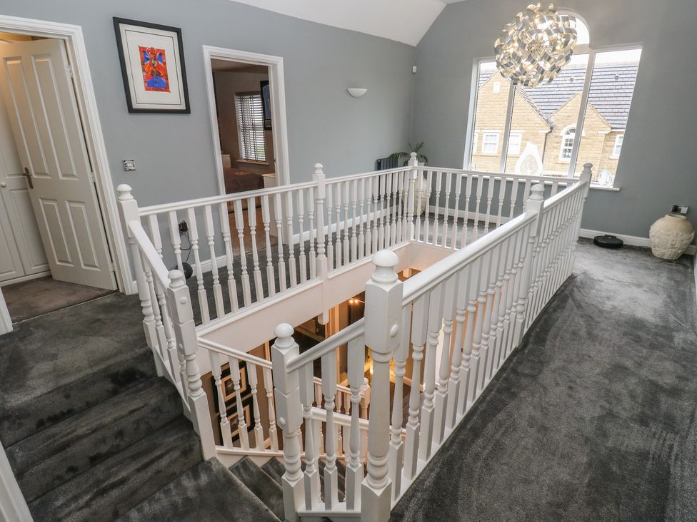 A hallway with a staircase and railing at 20 Overland Crescent in Apperley Bridge