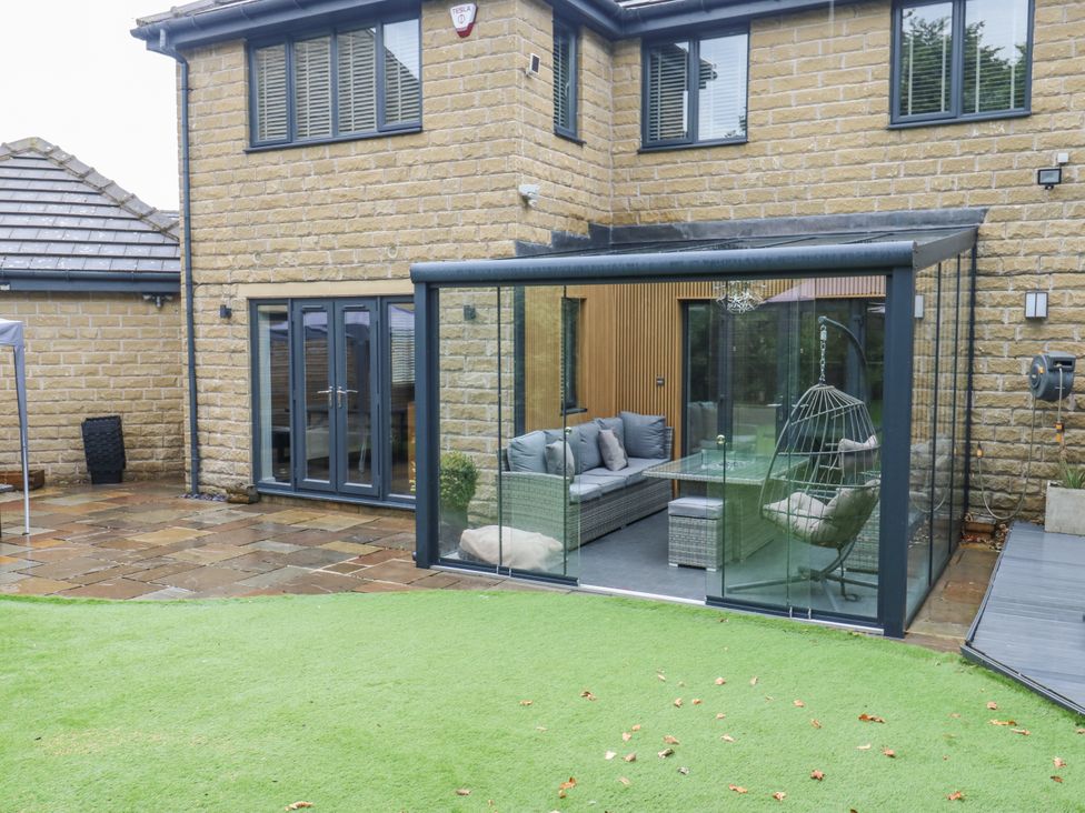 A garden with a glass enclosure and seating area at Corriegale in Apperley Bridge
