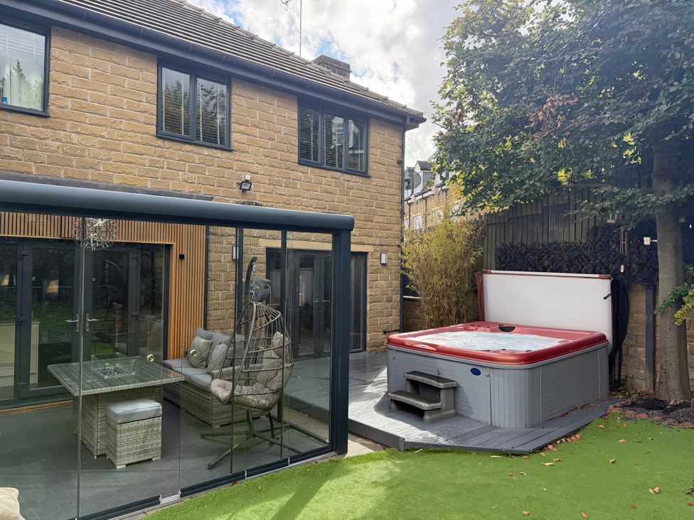 A garden with a hot tub and glass enclosure at Corriegale Apperley Bridge