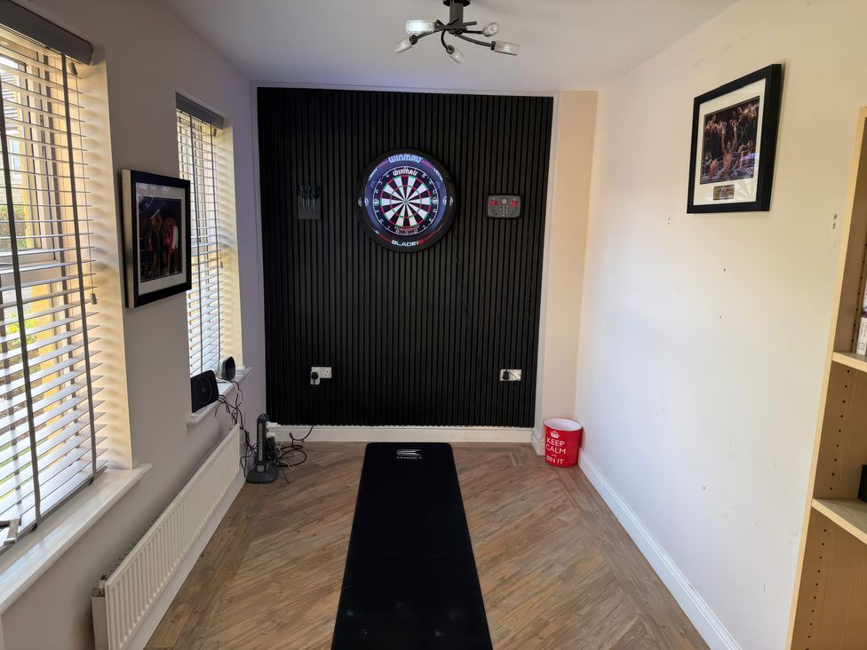 A game room with a dartboard and seating area at Corriegale in Apperley Bridge