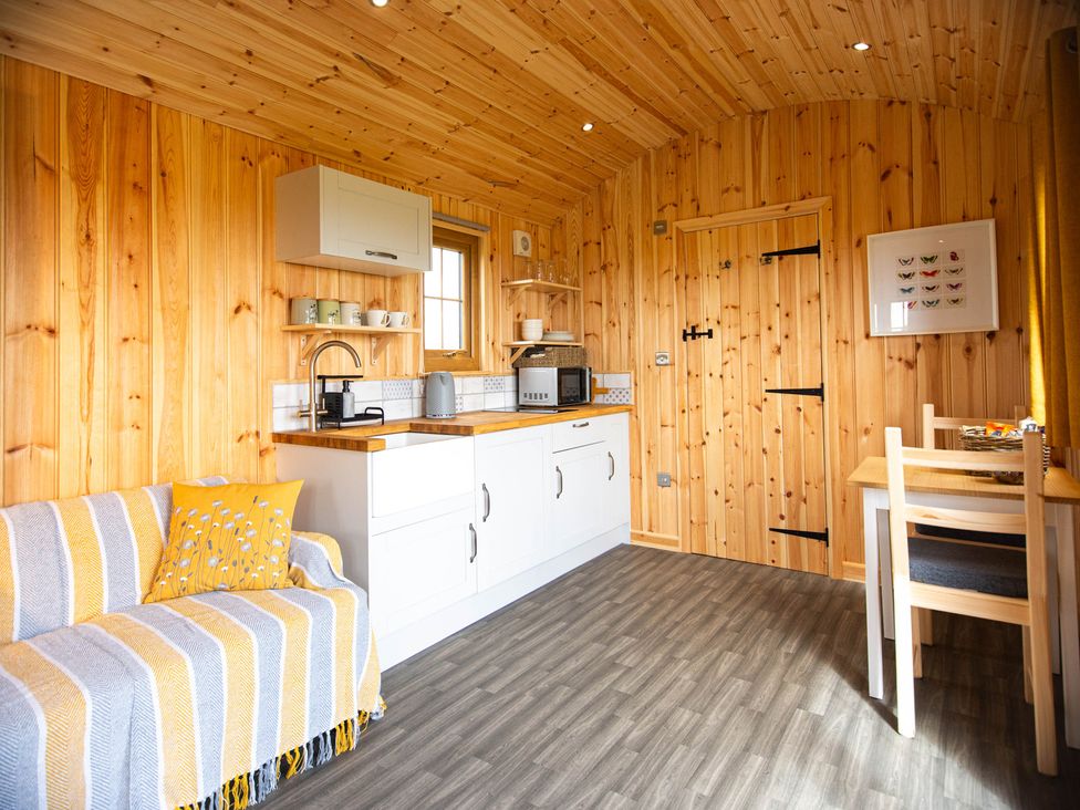 A kitchen with wooden walls and a table at Head For the Hills Glamping - Skylark Shepherd's Hut