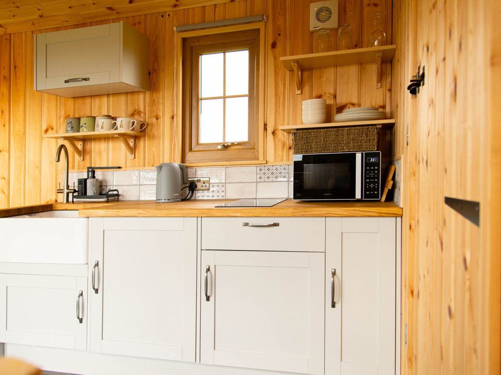 A kitchen with cabinets and appliances at Head For the Hills Glamping - Skylark Shepherd's Hut