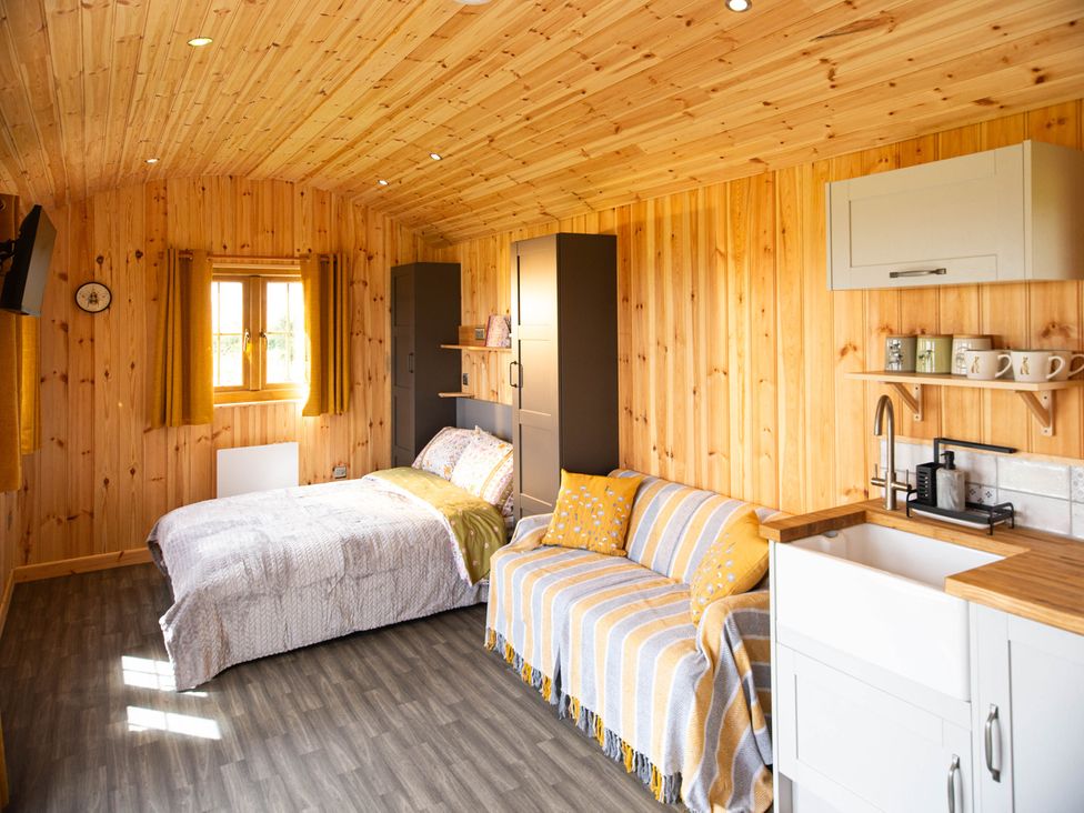 A sleeping area with a bed and a sofa at Head For the Hills Glamping - Skylark Shepherd's Hut
