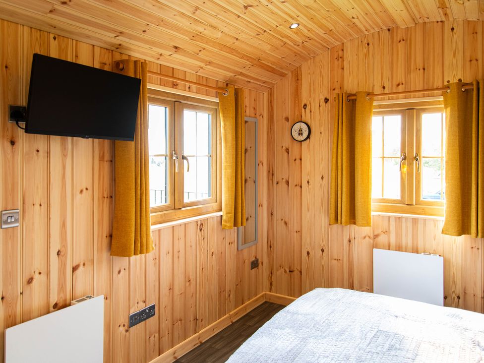 A bedroom with a television and windows at Head For the Hills Glamping - Skylark Shepherd's Hut