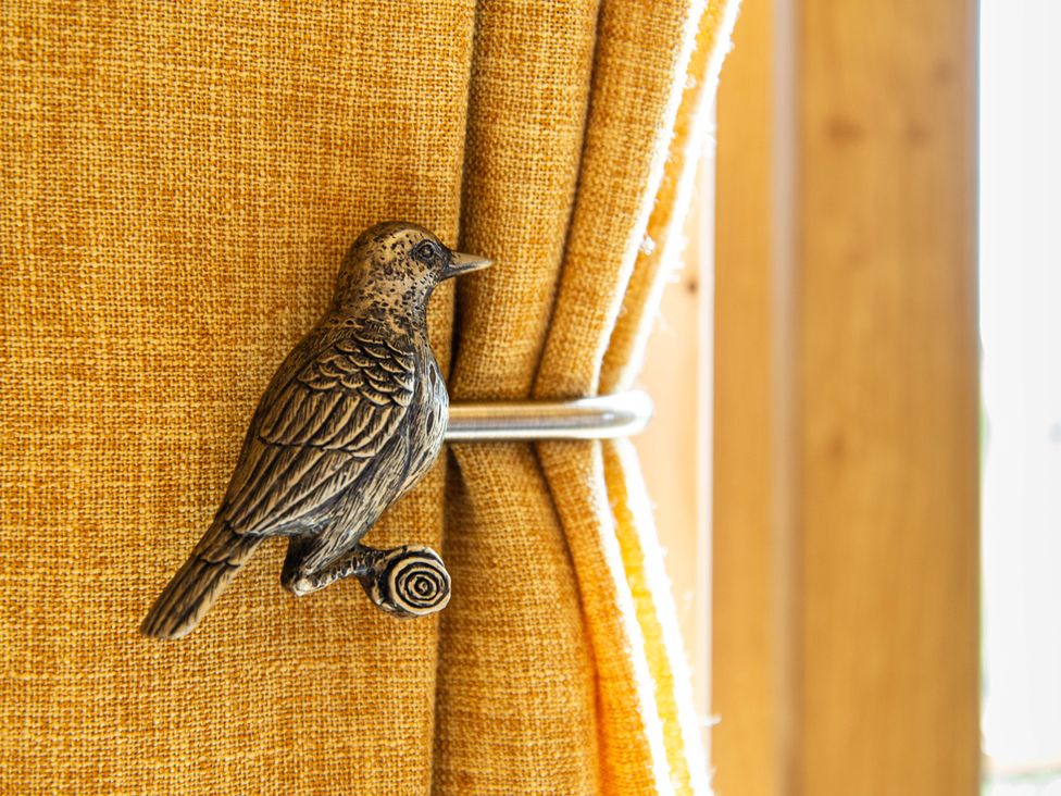 A curtain with a bird tieback at Head For the Hills Glamping - Skylark Shepherd's Hut