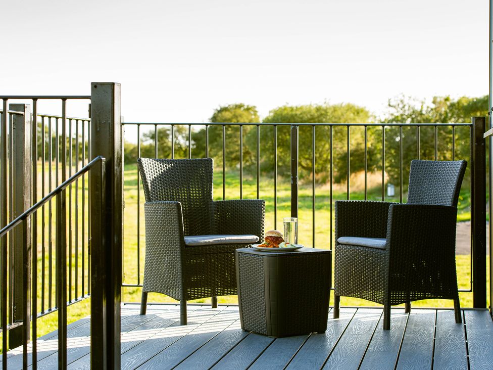 A patio with two chairs and a table holding a drink and food at Head For the Hills Glamping - Skylark Shepherd's Hut