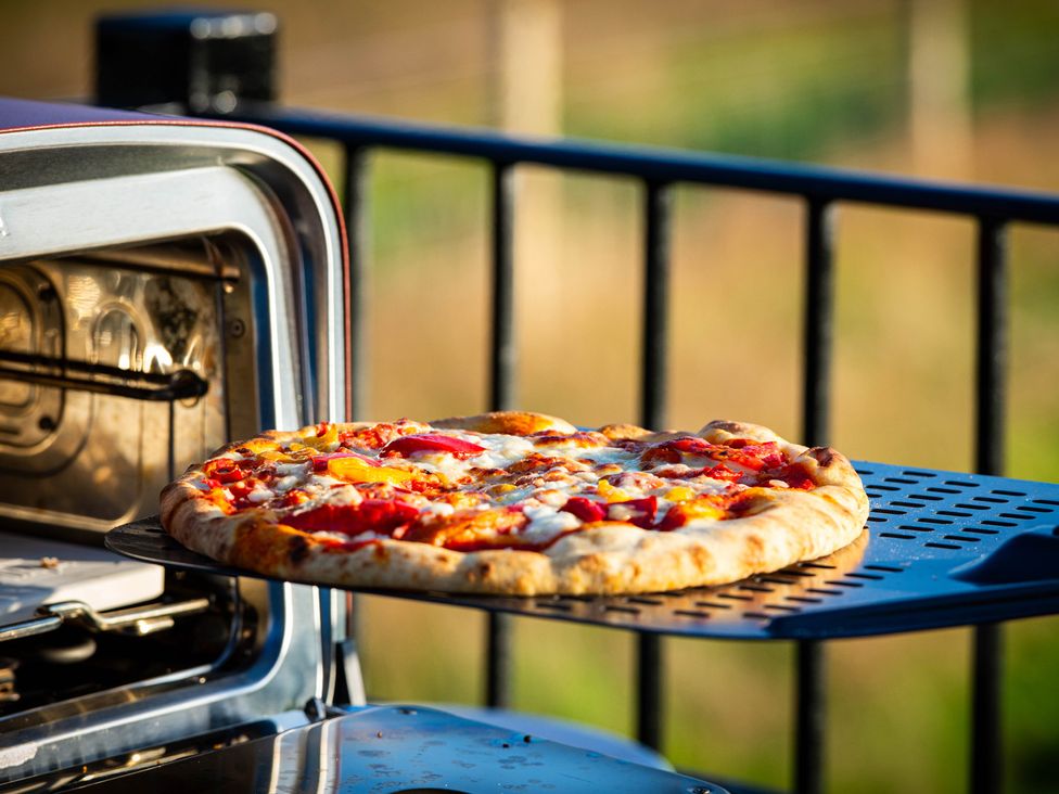 A pizza on an outdoor pizza oven at Head For the Hills Glamping - Skylark Shepherd's Hut