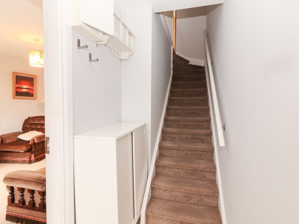 A hallway with a staircase and storage cabinet at 1 Windermere in Kinvarra