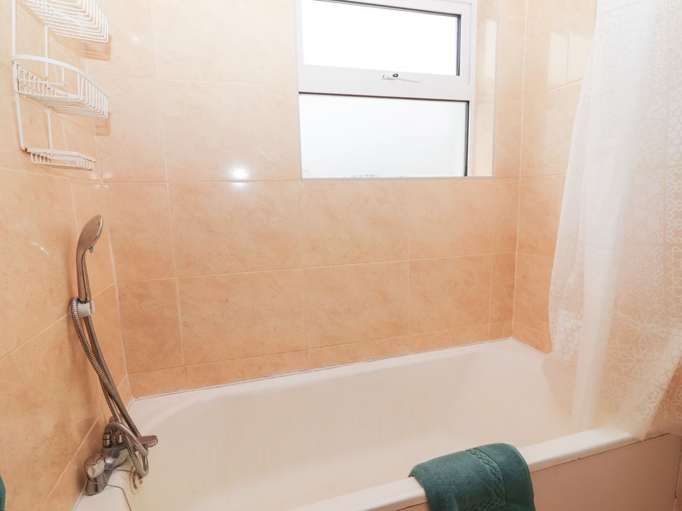 A bathtub with a showerhead and towel at 1 Windermere in Kinvarra