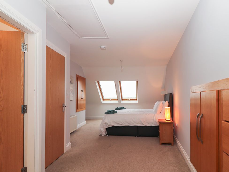 A bedroom with a bed and windows at 1 Windermere in Kinvarra