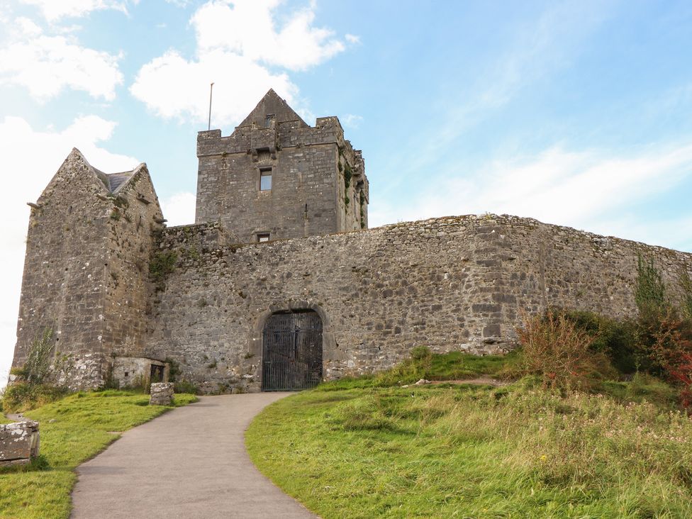 A castle with a stone wall and pathway at 1 Windermere in Kinvarra