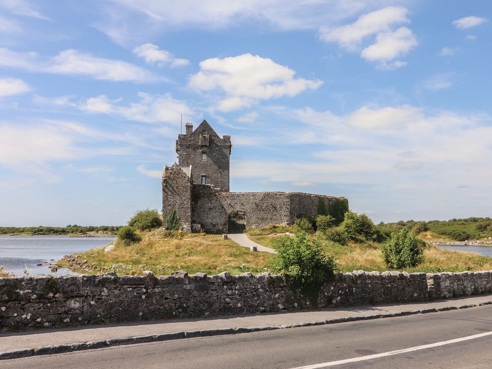 A castle next to a river with a stone wall along the road at 1 Windermere, Kinvara, County Galway