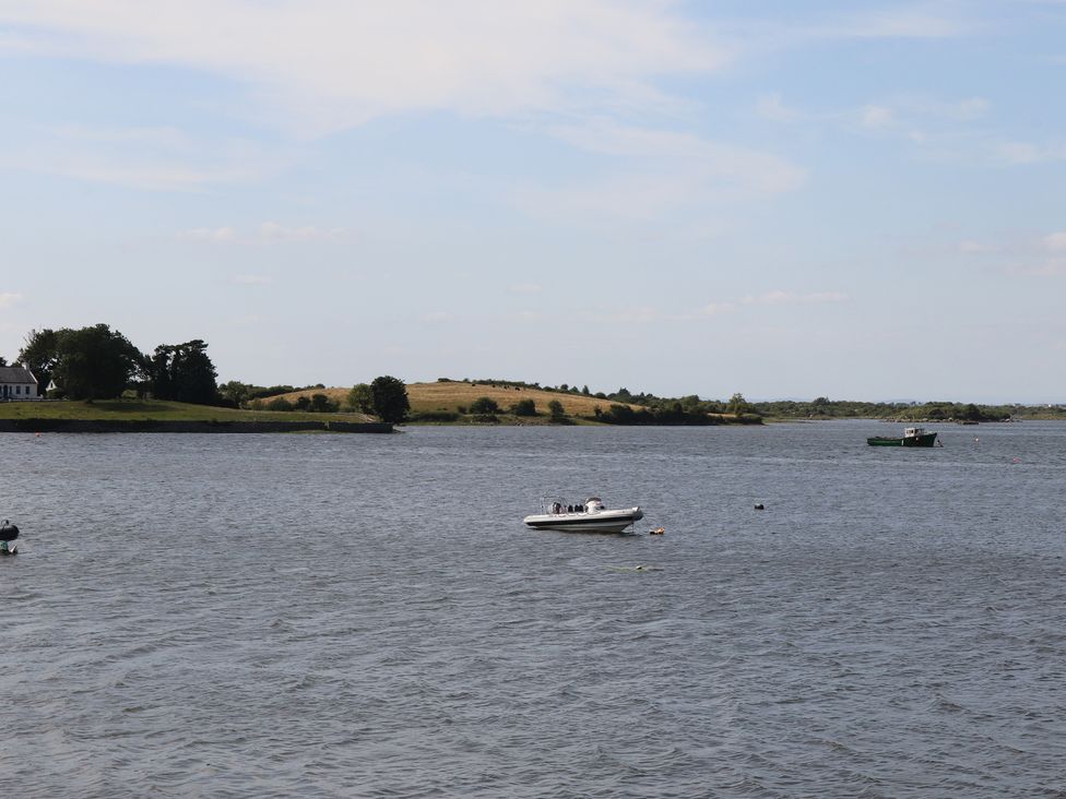 A boat on a body of water with land and trees in the background at 1 Windermere Kinvara, County Galway