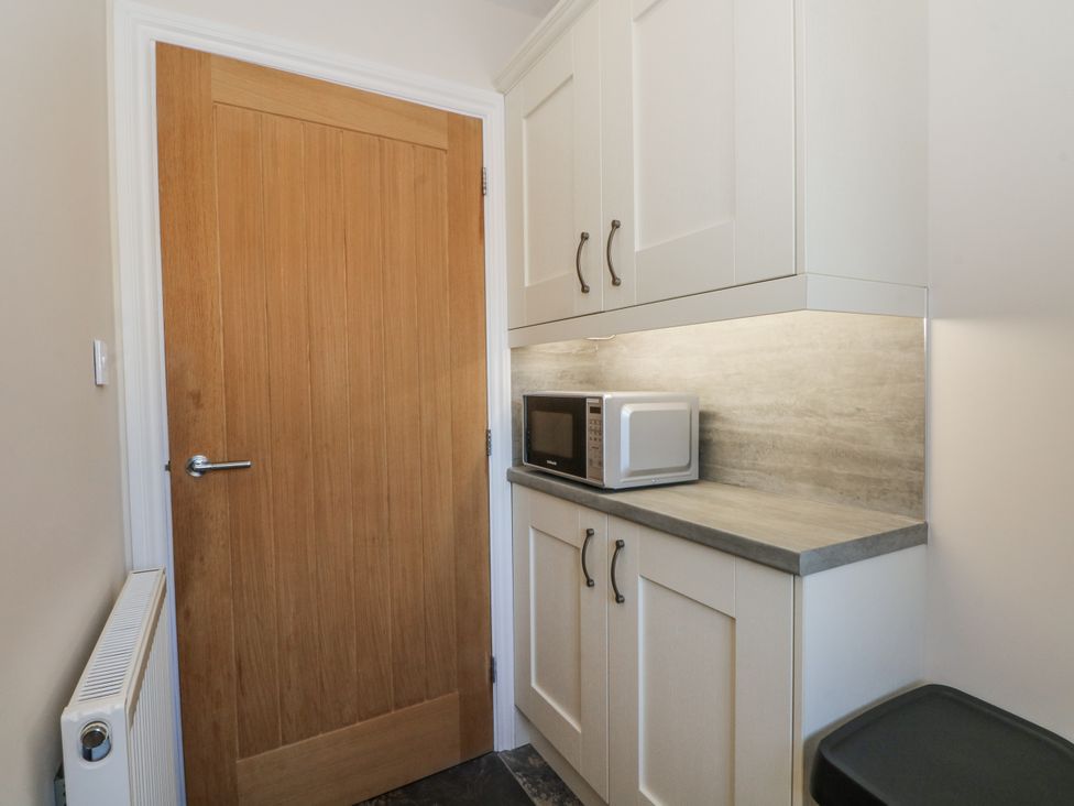 A utility room with cupboards and a microwave at The Annexe in Caverswall