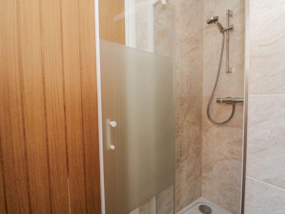 A shower with a glass door and wall tiles at The Annexe in Caverswall