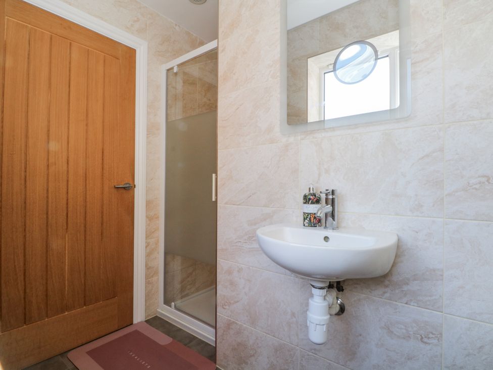 A bathroom with a sink, shower, and mirror at The Annexe in Caverswall