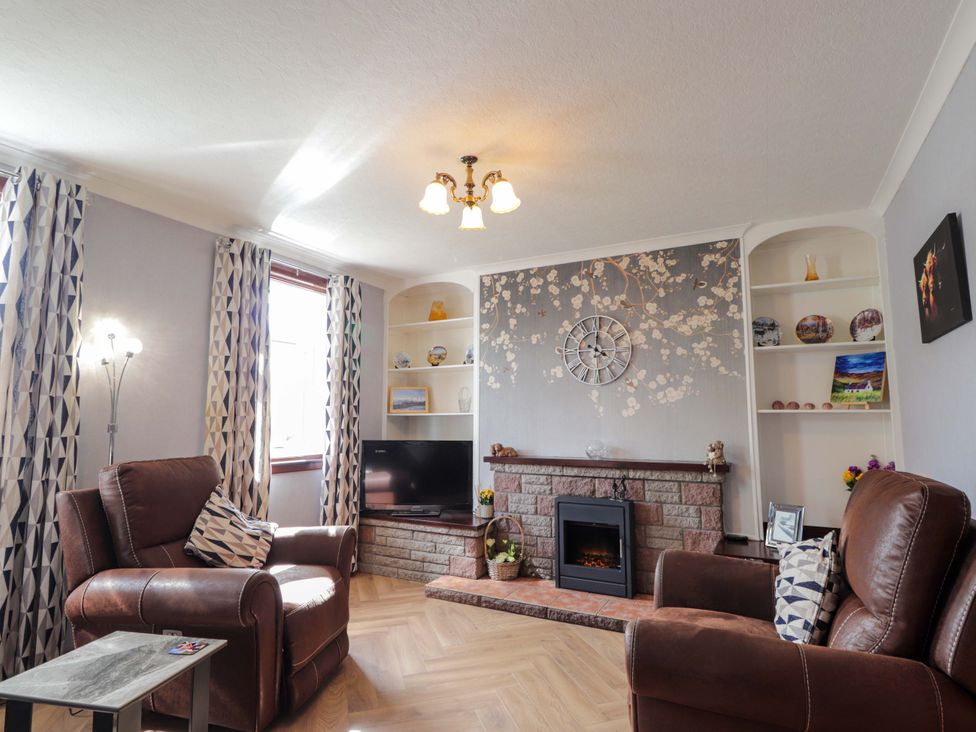 A living room with a fireplace and a TV at The Highlander in Dornie