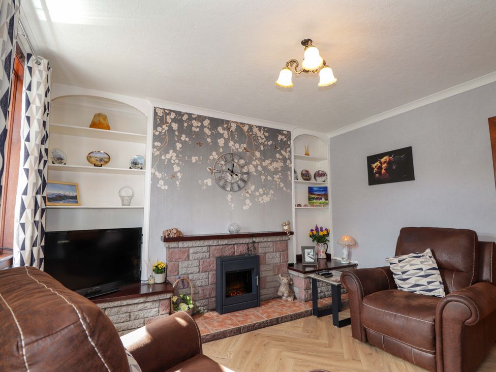 A living room with a fireplace and television at The Highlander in Dornie
