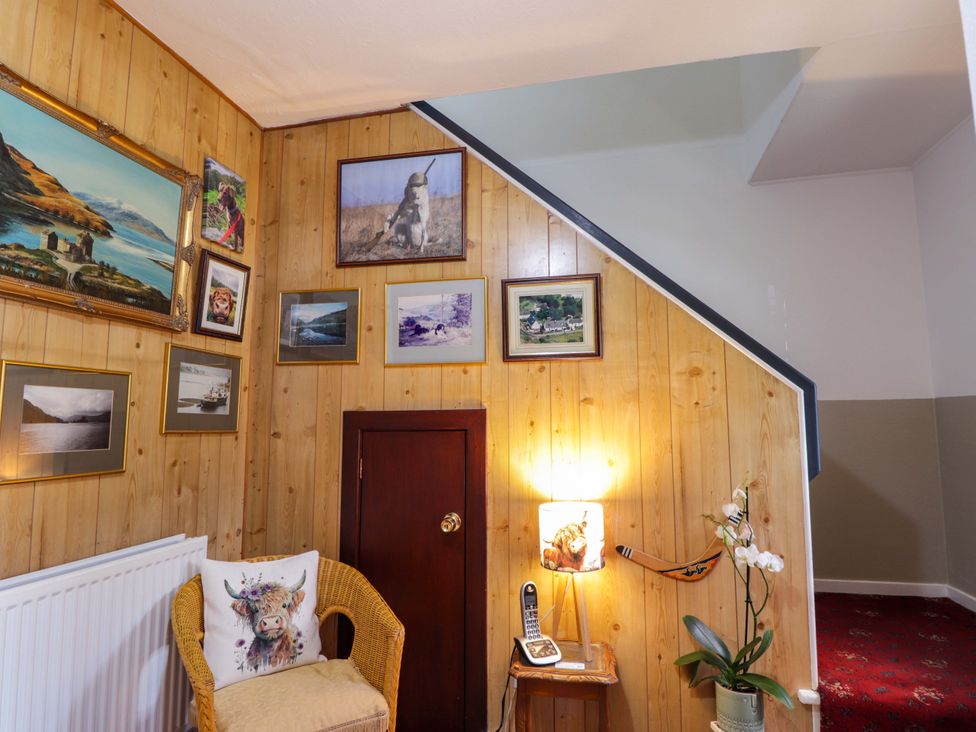 A hallway with wooden walls and pictures at The Highlander in Dornie
