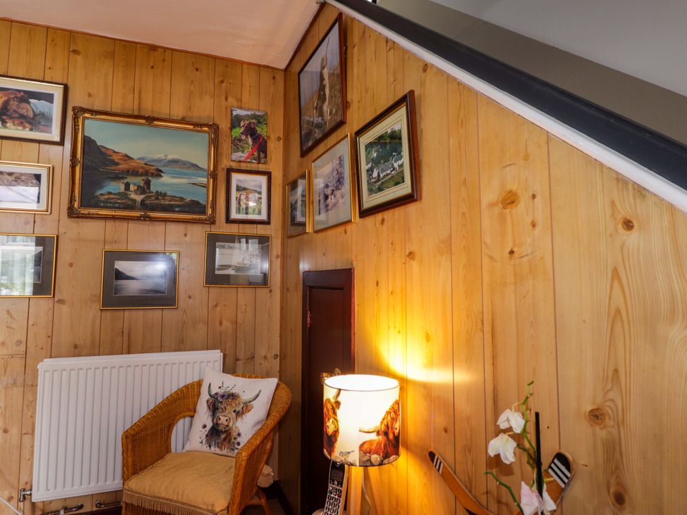 A snug with wooden walls and various pictures at The Highlander in Dornie