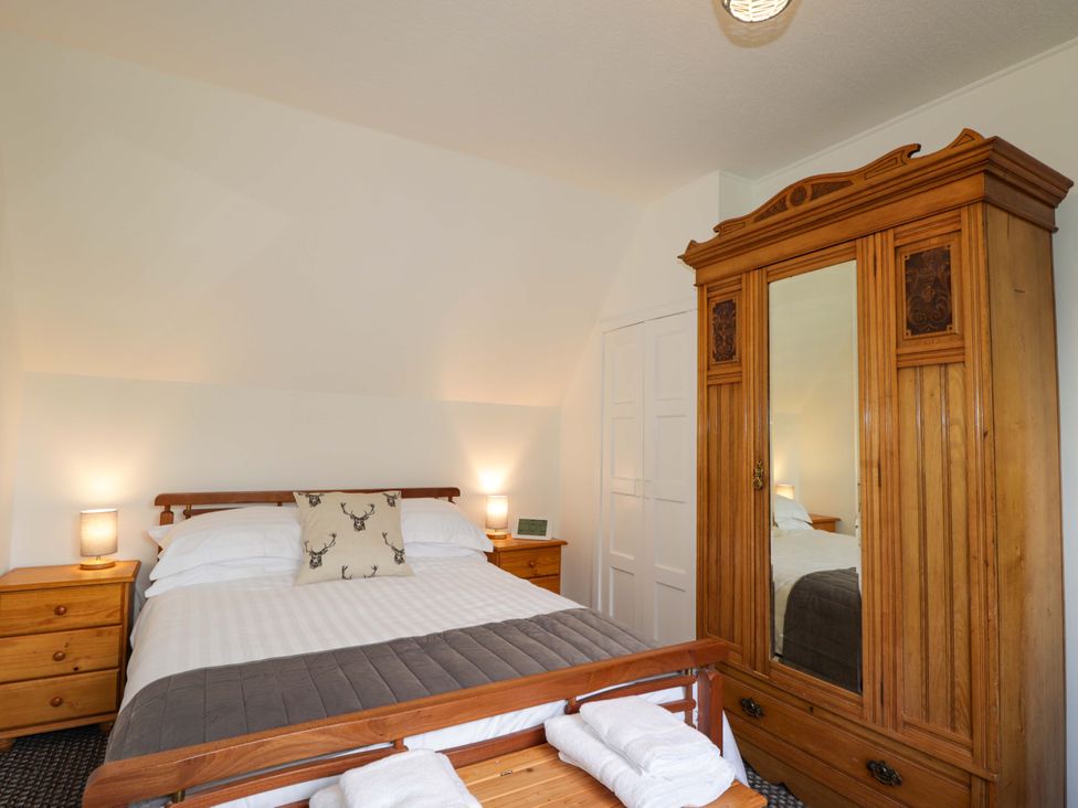 A bedroom with a bed and wardrobe at The Highlander in Dornie