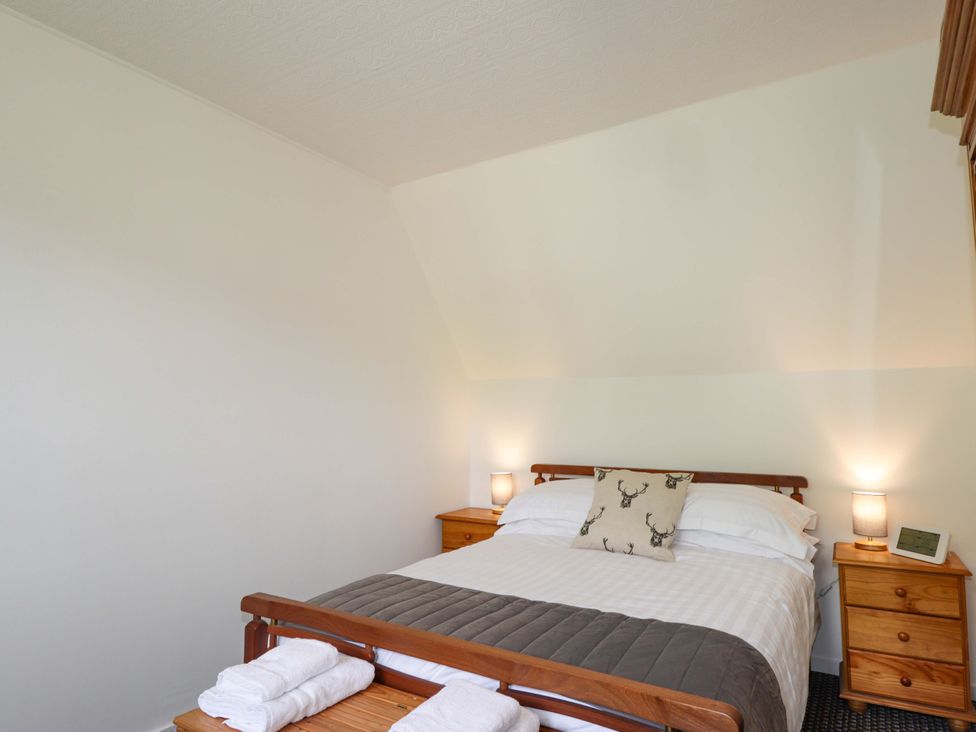 A bedroom with a bed and nightstands at The Highlander in Dornie