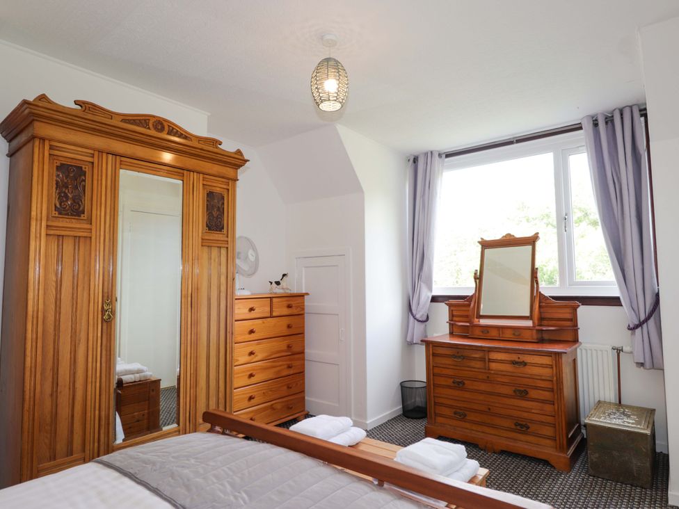 A bedroom with wooden furniture and a window at The Highlander in Dornie