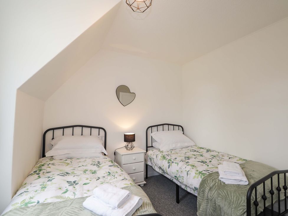 A bedroom with two beds and a bedside table at The Highlander in Dornie