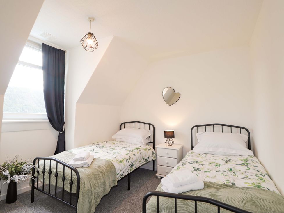 A bedroom with two beds and a nightstand at The Highlander in Dornie