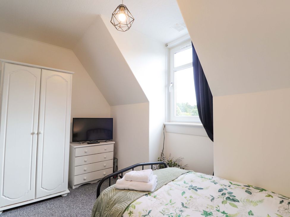 A bedroom with a bed, wardrobe, television, and dresser at The Highlander in Dornie