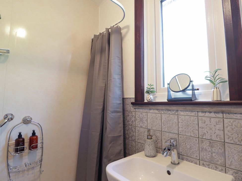 A bathroom with shower curtain and sink at The Highlander in Dornie