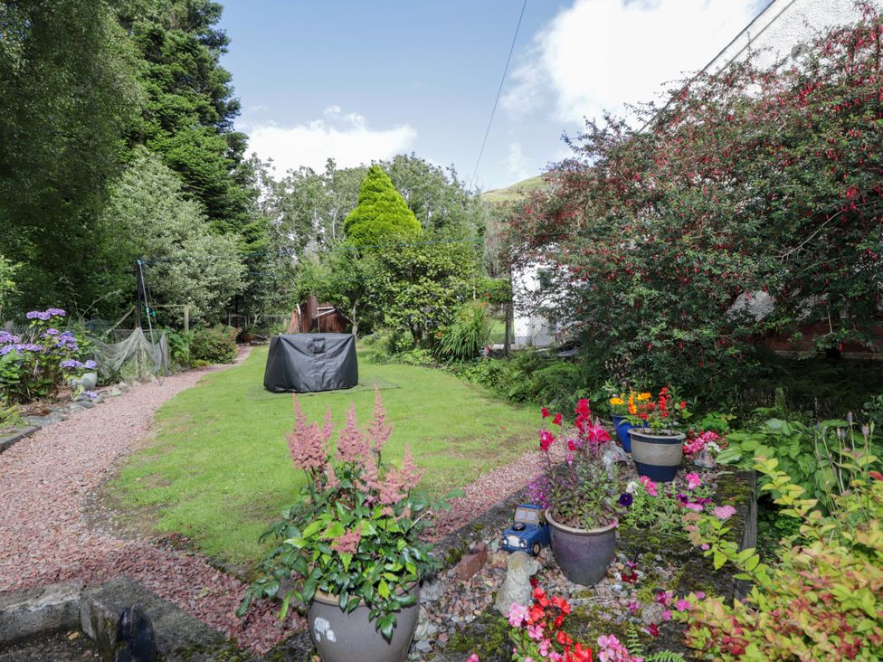 A garden with flower pots and a pathway at The Highlander in Dornie
