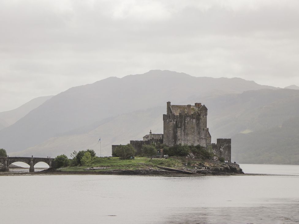 A castle with a bridge over water at The Highlander in Dornie