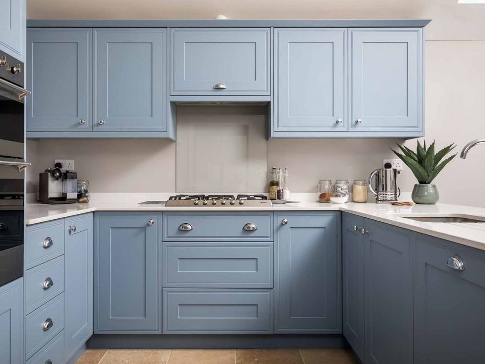 A kitchen with blue cabinets and a stove at Lavender Cottage (Stow-on-the-Wold) Cheltenham