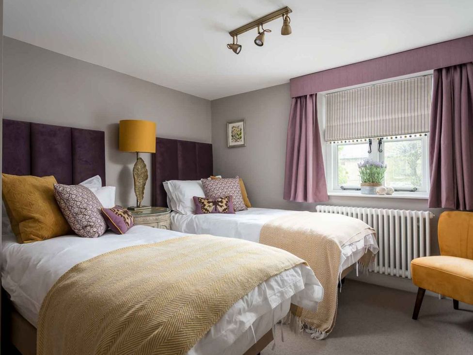 A bedroom with two beds and a chair at Lavender Cottage (Stow-on-the-Wold), Cheltenham